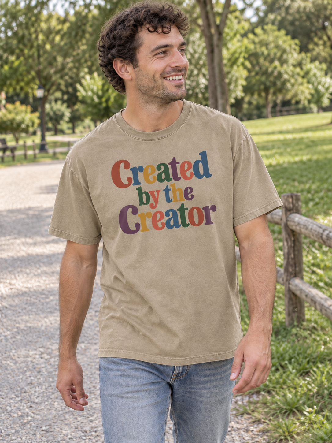 Khaki Created by the Creator tee worn on a park path, front design.