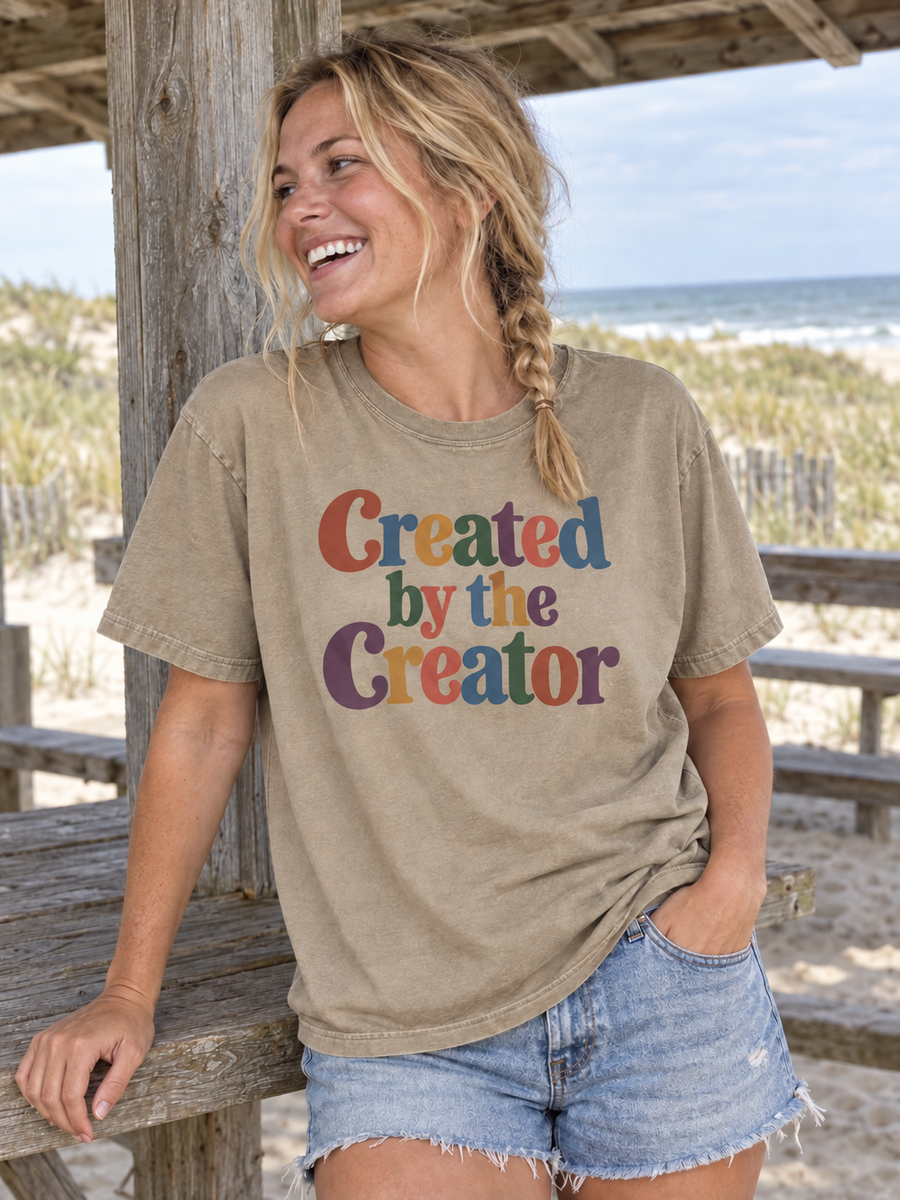 Khaki Created by the Creator tee at a coastal picnic shelter.