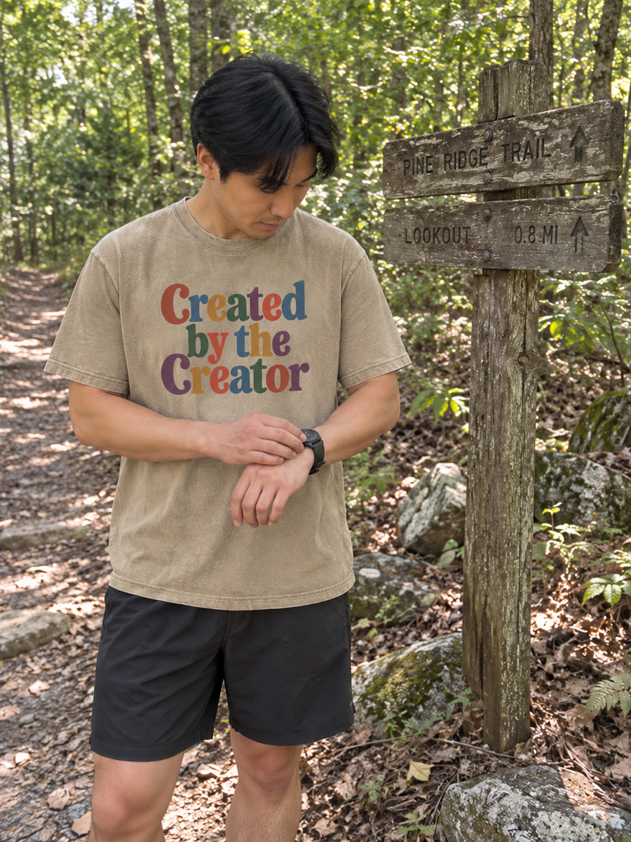 Khaki Created by the Creator tee at a woodland trail sign.