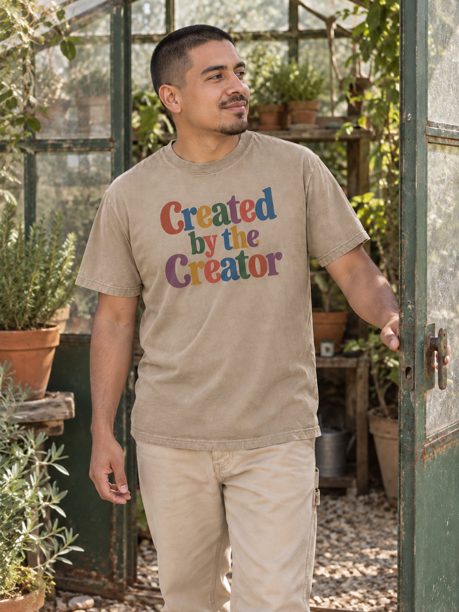 Khaki Created by the Creator tee beside a backyard greenhouse.