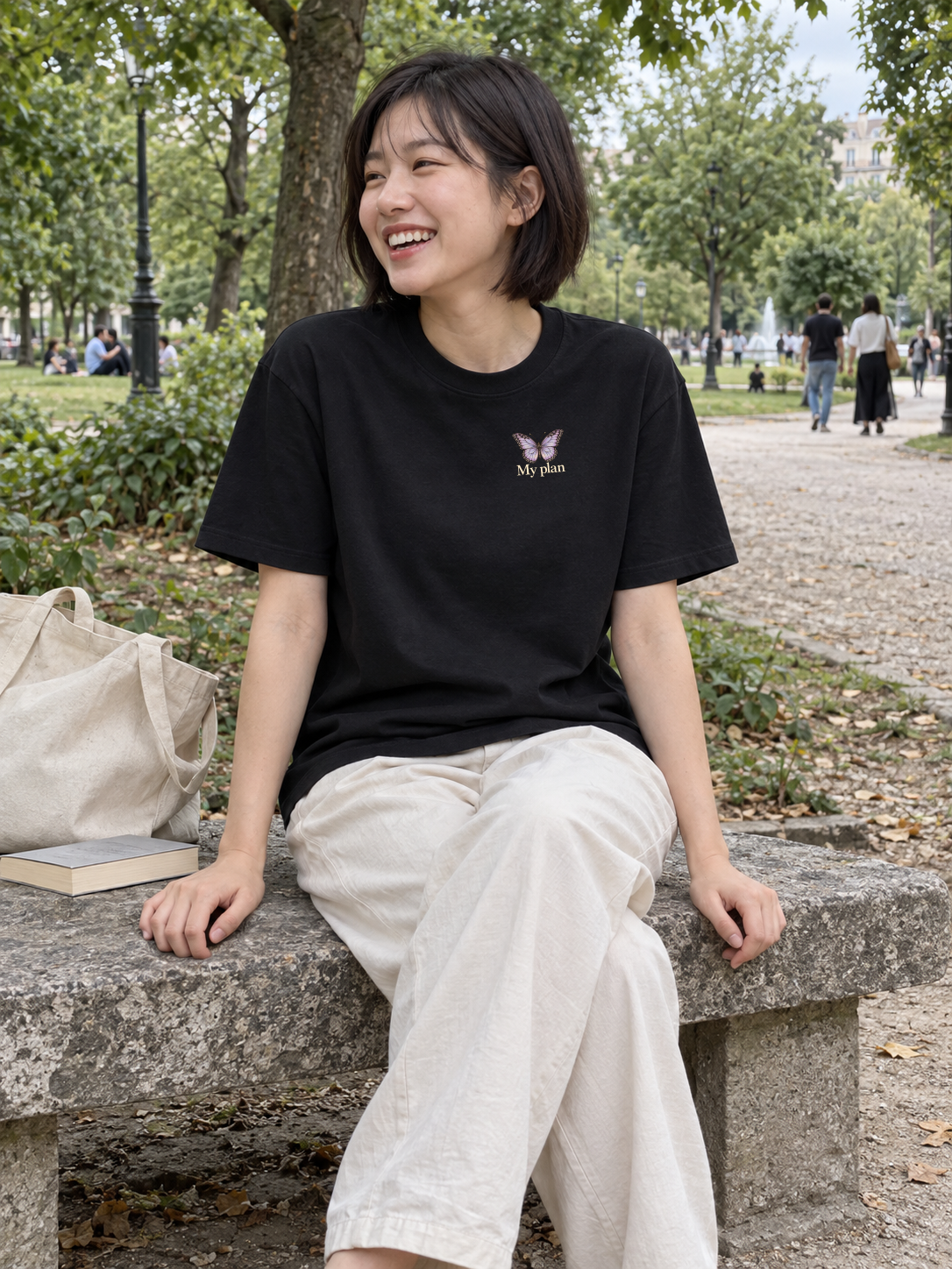 God’s Plan Tee front chest print on a woman seated in a leafy park
