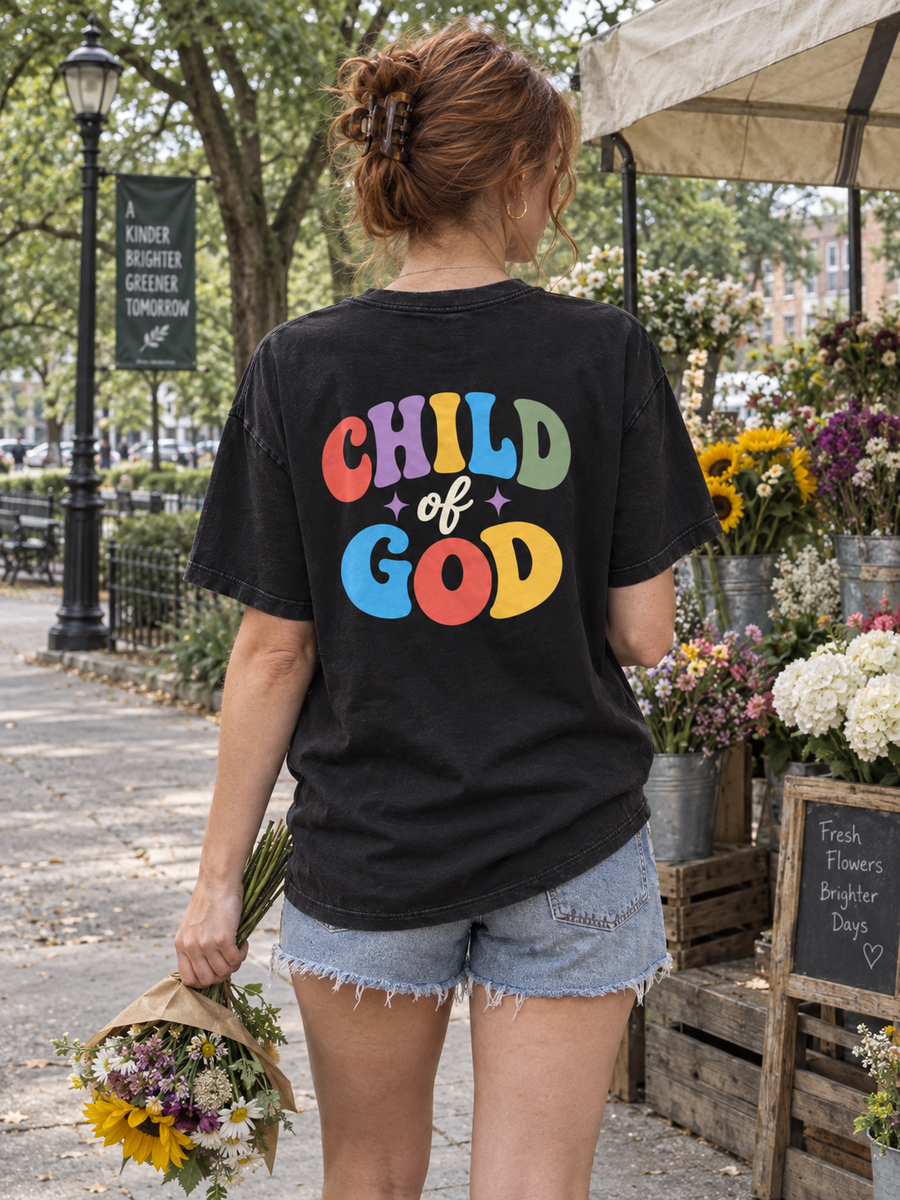 Woman showing the Child of God back print while holding flowers at an outdoor market.