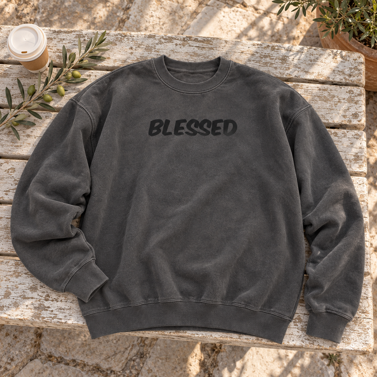 washed warm dark charcoal crewneck, black bold italic BLESSED centered chest — square editorial flat lay