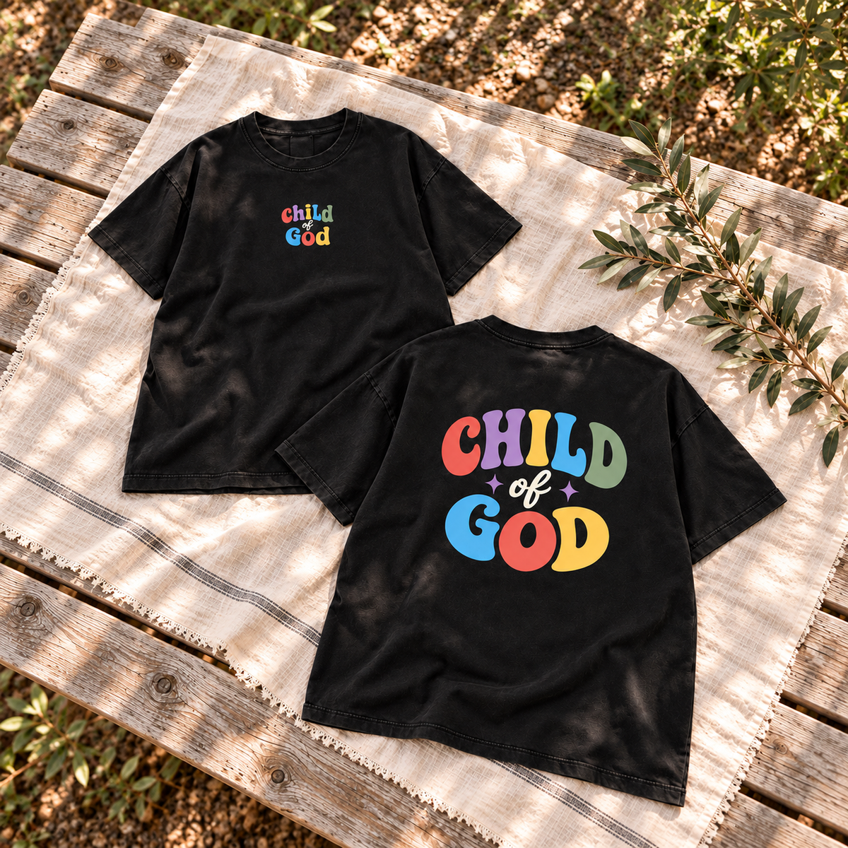 Child of God Unisex Garment-Dyed Tee — Black — square editorial flat lay, AI-styled