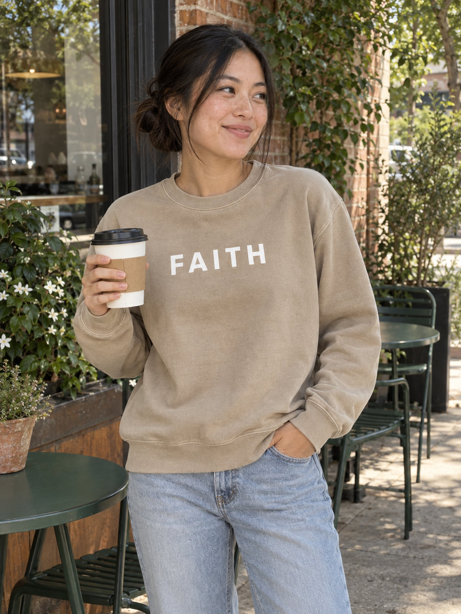 Faith Unisex Pigment-Dyed Crewneck Sweatshirt — Woman holding coffee at leafy café