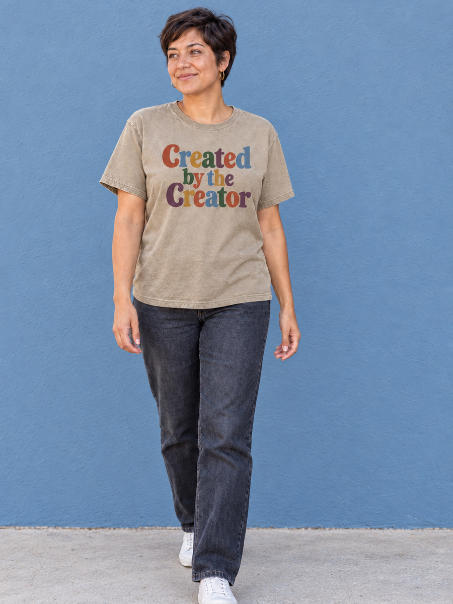 Created by the Creator Khaki tee, natural walk-in against a clean powder-blue wall.