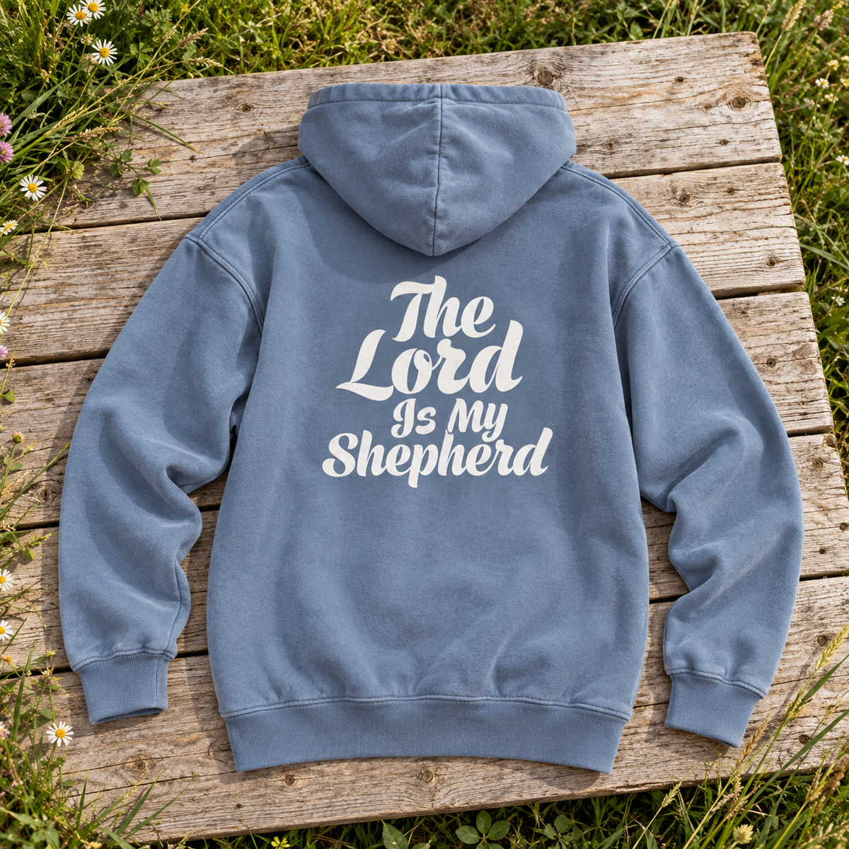 washed dusty blue hoodie viewed from back, white calligraphic The Lord Is my Shepherd in same line breaks and script as reference — square editorial flat lay