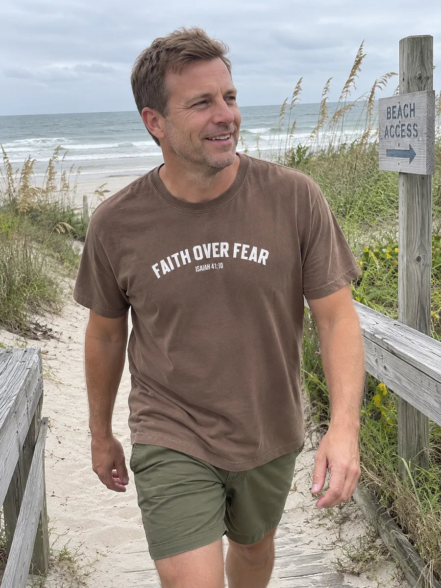 AI-created scene of a man wearing the brown Faith Over Fear tee on a beach access path