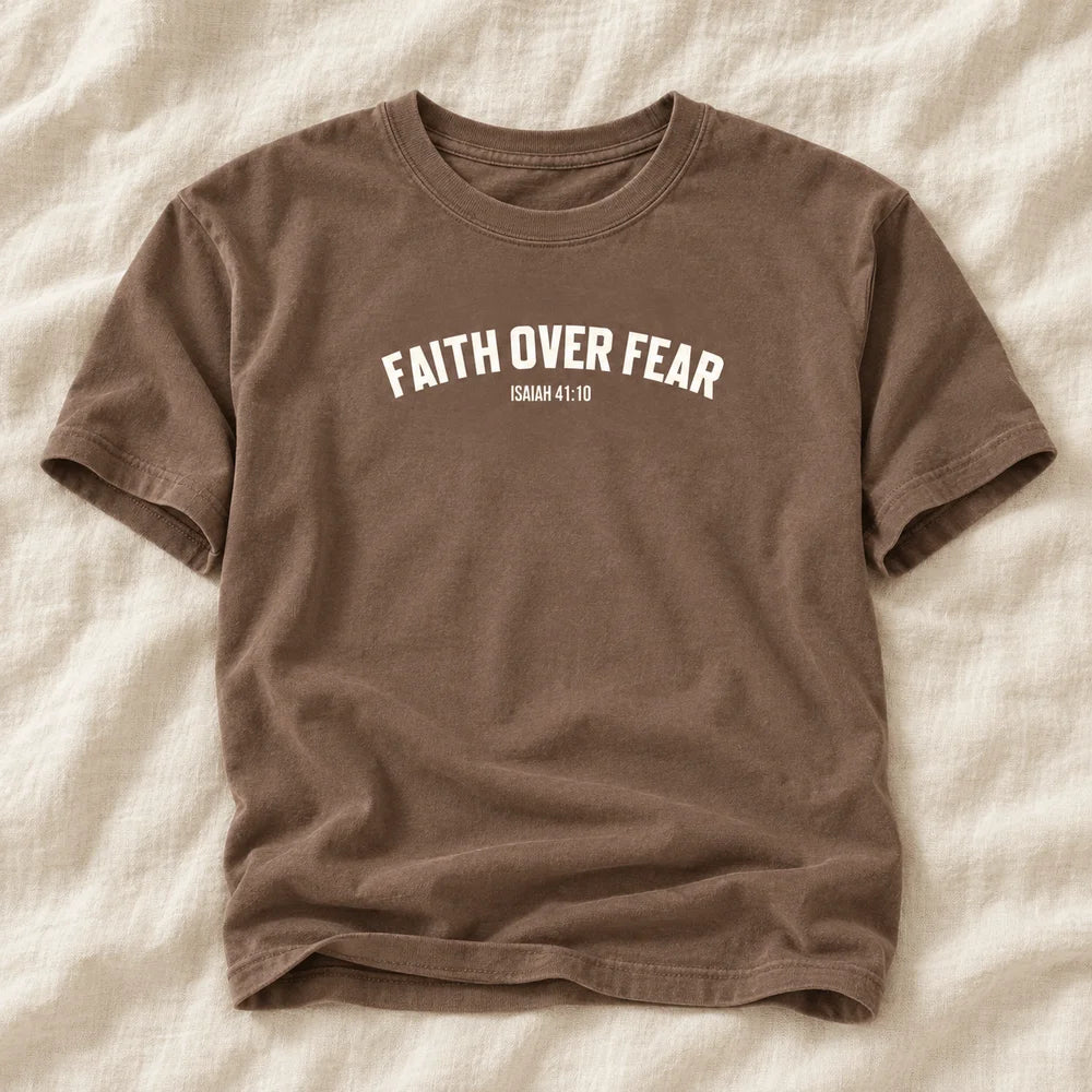 Flat-lay mockup of the brown Faith Over Fear tee on warm ivory linen