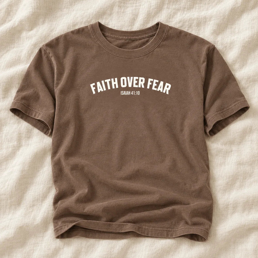 Flat-lay mockup of the brown Faith Over Fear tee on warm ivory linen