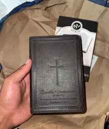 A customer holding a compact Bible with a cross and personal inscription
