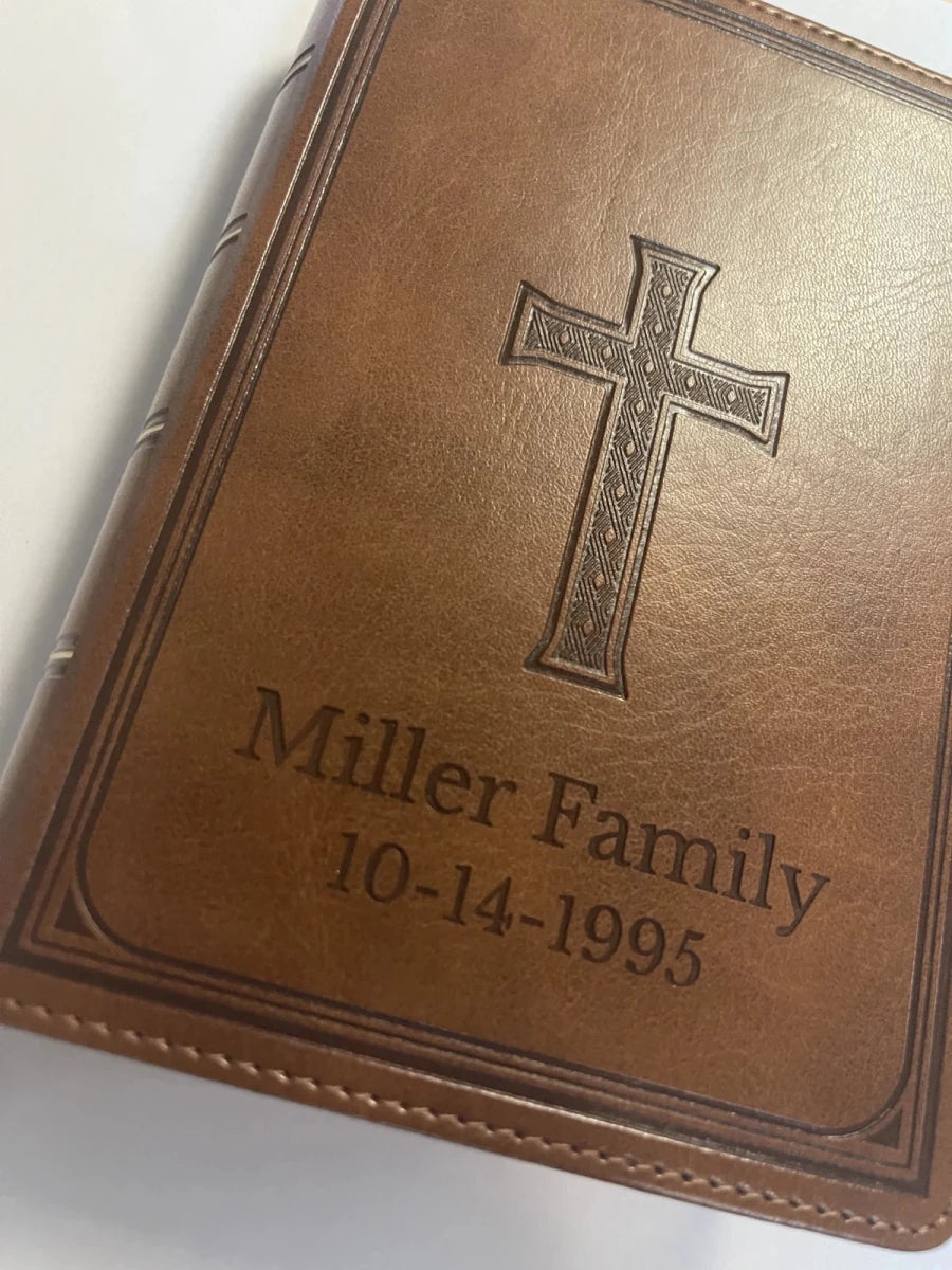 Close-up of a brown Bible engraved with a decorative cross, Miller Family and 10-14-1995